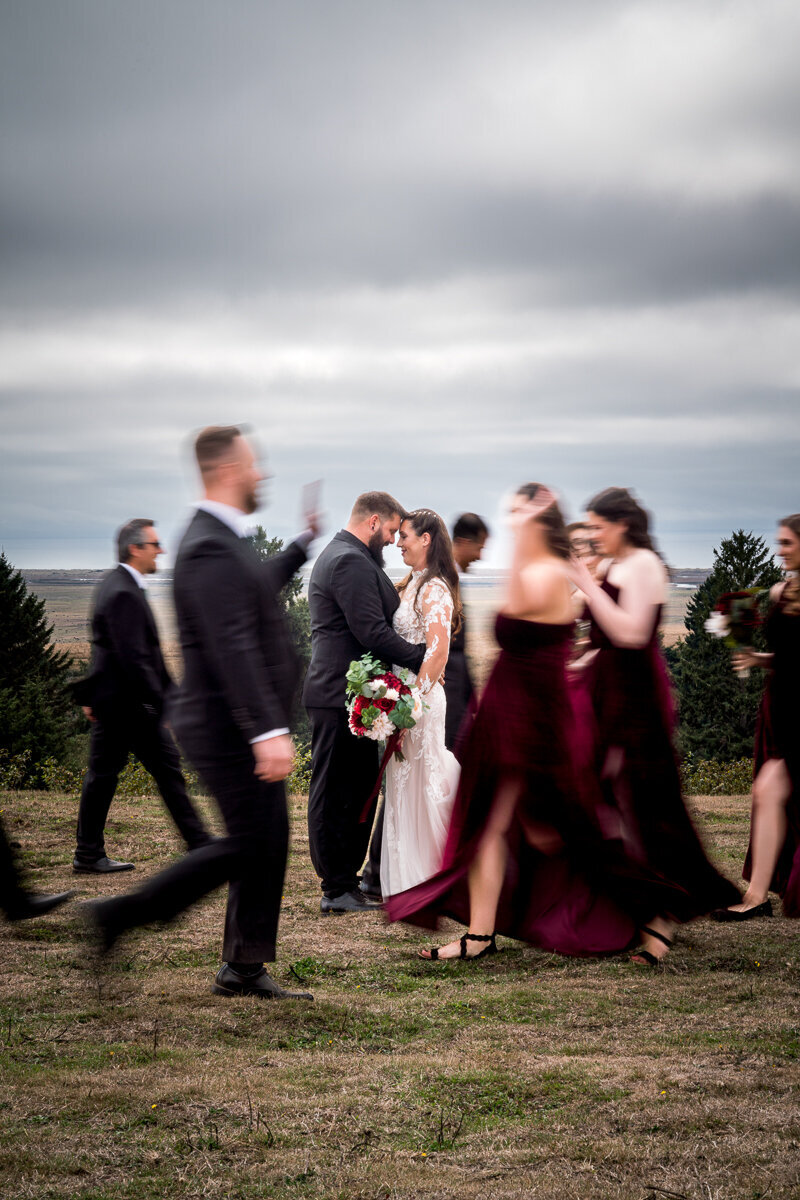 A playful wedding moment featuring the bride and groom sharing a laugh while the bridal party walks around them in a beautifully blurred motion. Captured at the North Coast Hitching Post in Loleta, this shot highlights the couple’s joy and the lively energy of their special day in a rustic and charming setting. Perfect for capturing unforgettable wedding memories in Humboldt County.