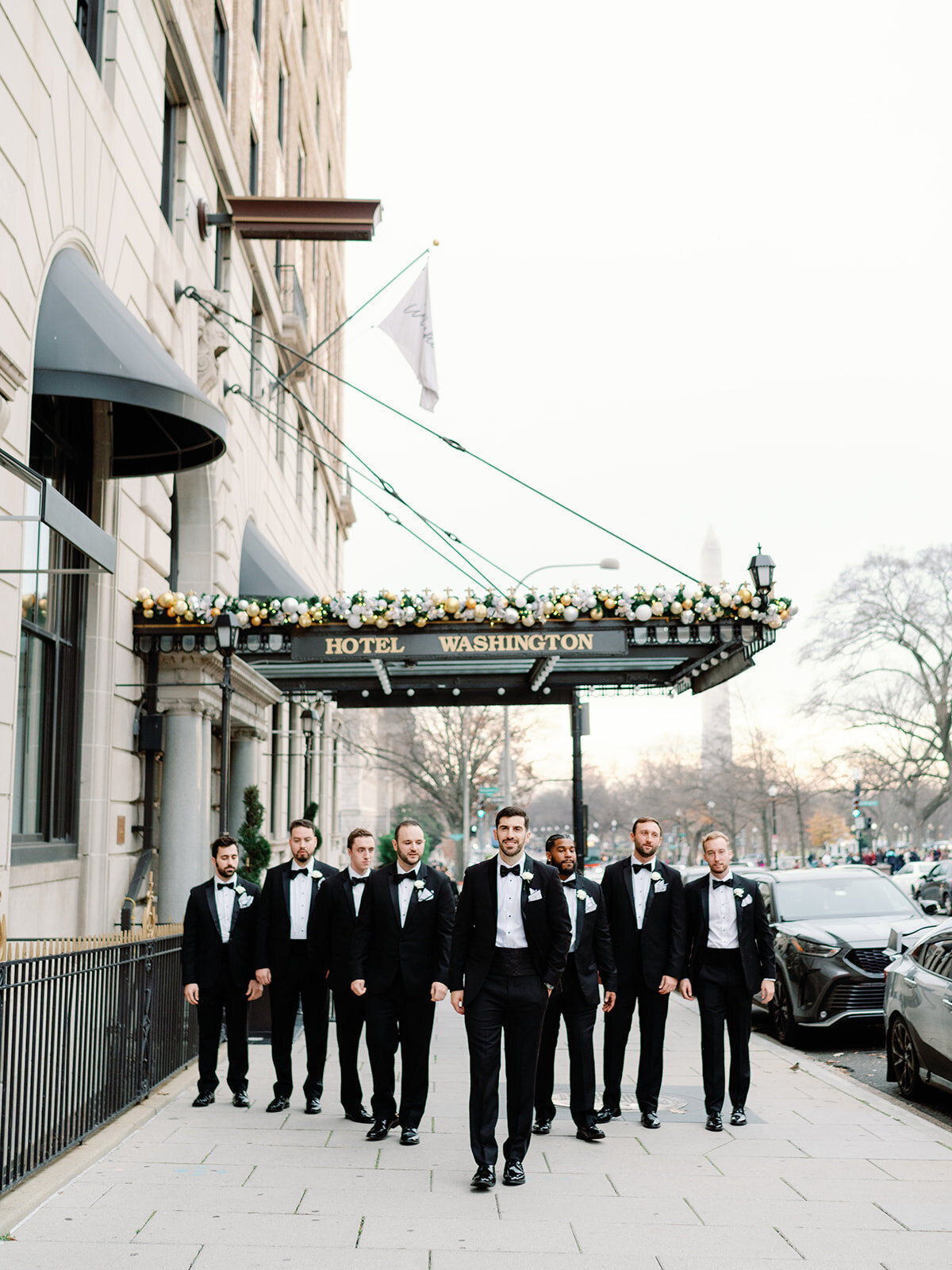 Groomsment walk down the street in front of Hotel Washington in DC