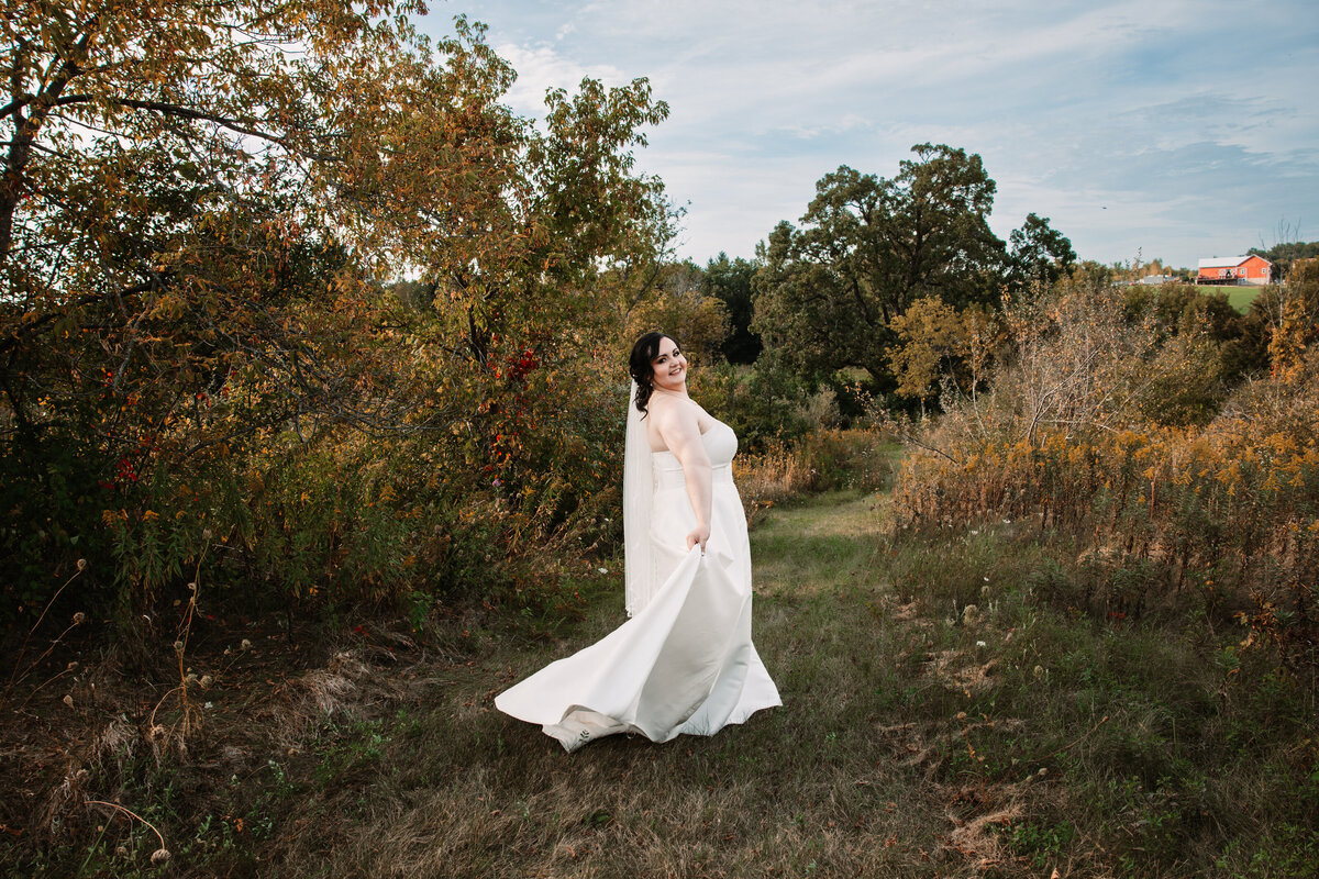 A bride walks and plays with her dress in a trail at sunset