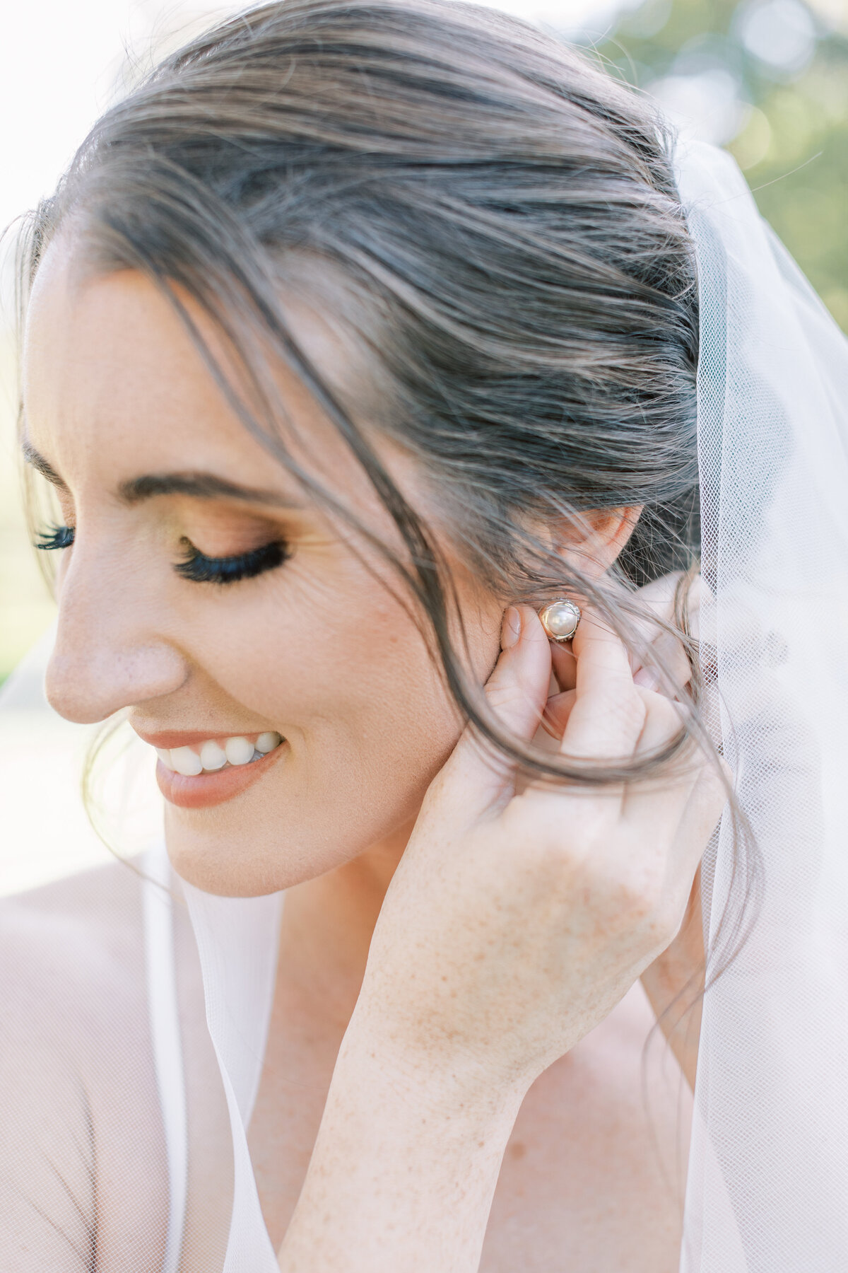 A joyful bride puts her earring in.