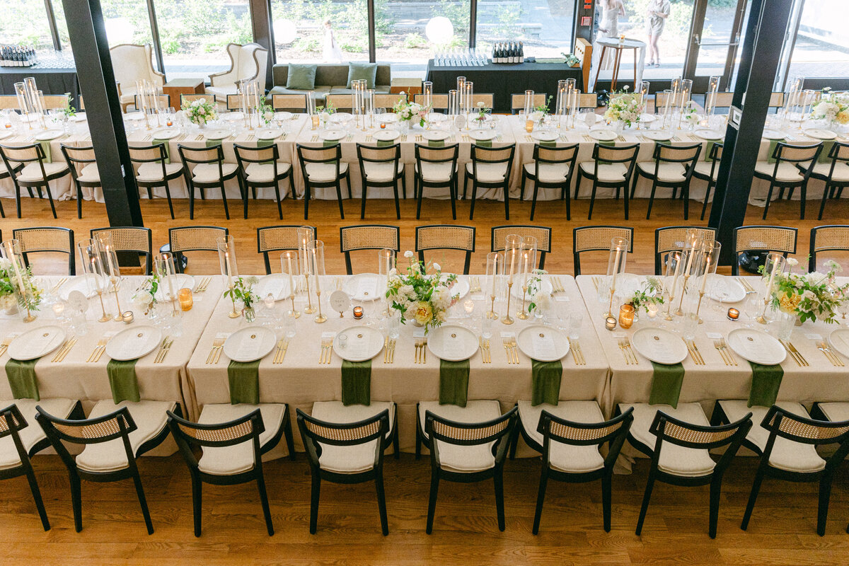 Long tables for a wedding at La Toundra decorated with green napkins and spring floral centrepieces.