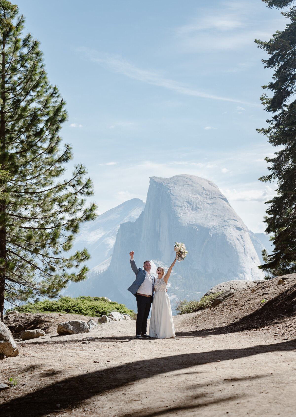 A couple with their hands up celebrating on a rocky mountain overlook