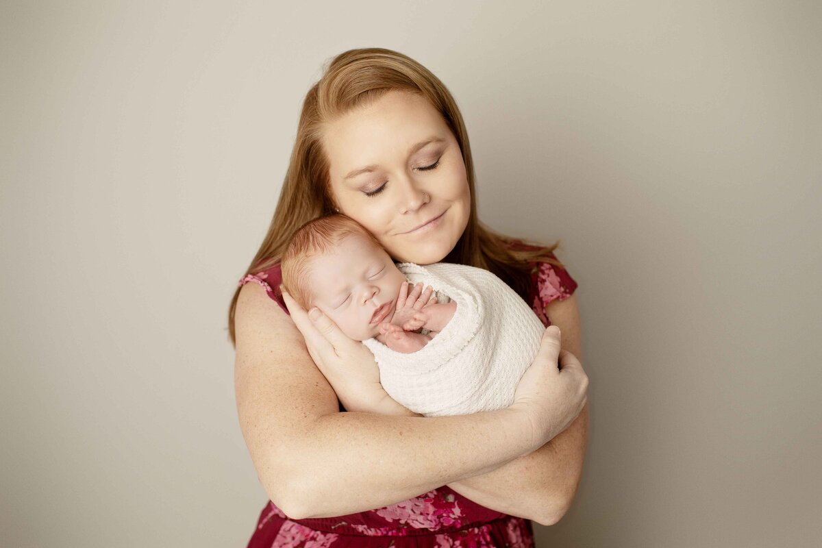 Mother holding her newborn son, both sharing a quiet, intimate moment
