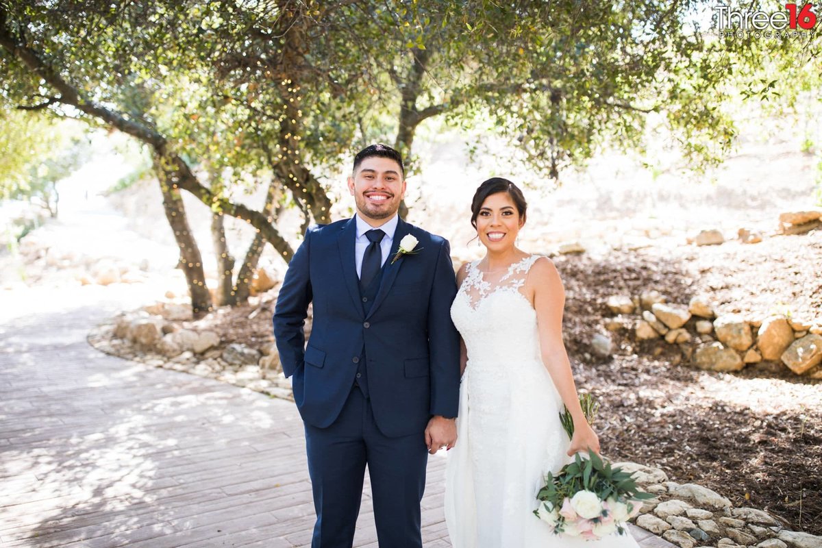 Bride and Groom pose for the camera under a giant tree