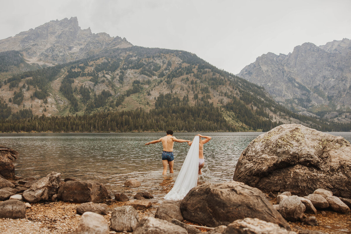 bride and groom jumping in lake