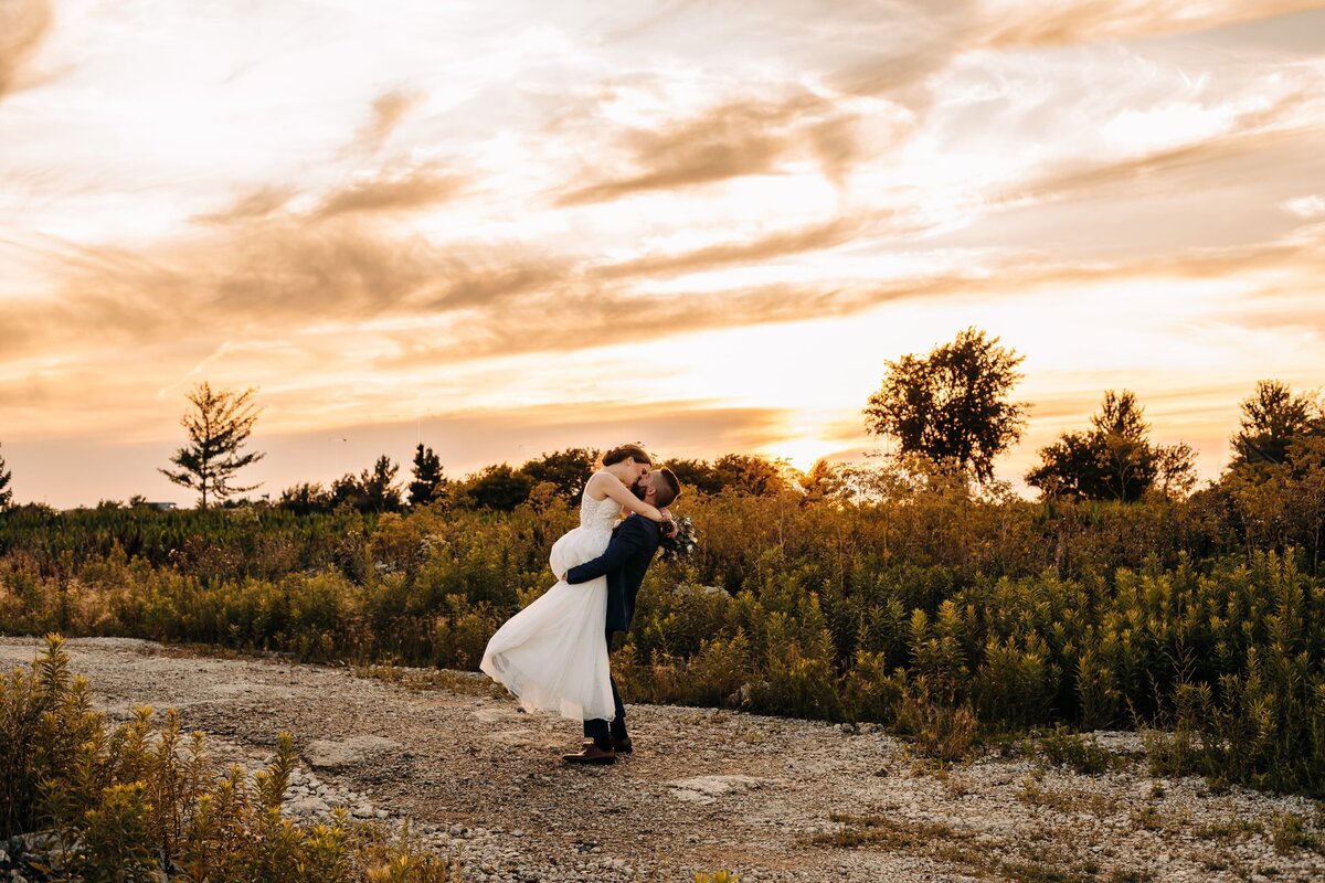 married couple kissing on road during sunset