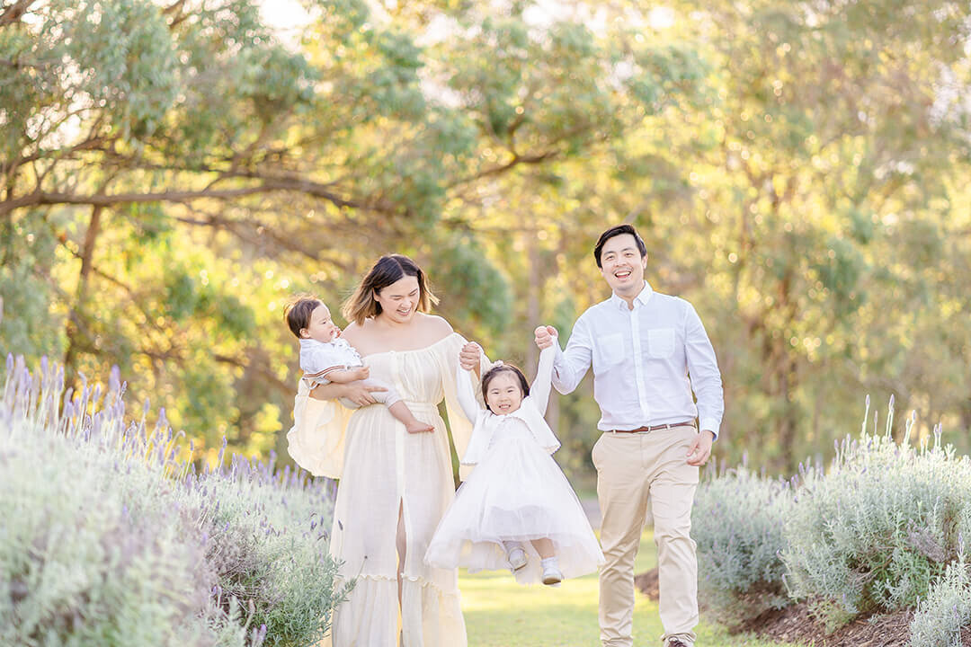 Family of 4 swinging toddler around for fun, interactive photos with family photographer Hikari Lifestyle Photography.