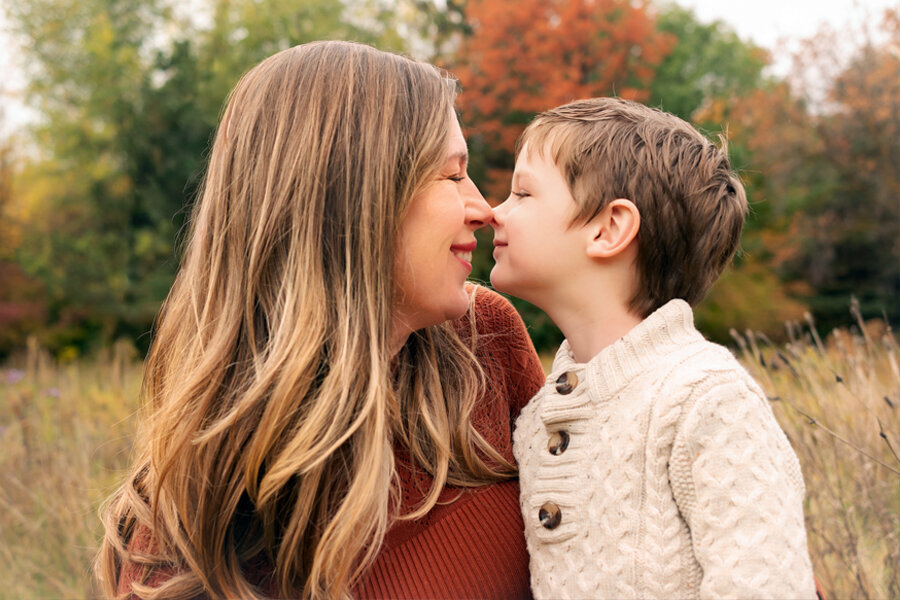 Mother and son rubbing noses with fall background.