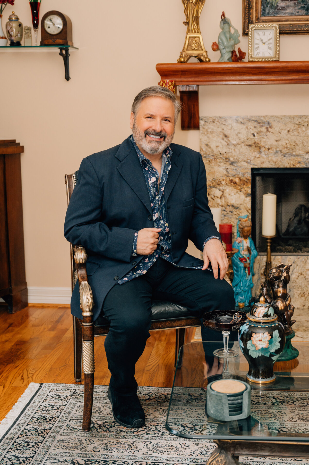 Ernie Manouse sitting confidently in formal attire by fireplace in Houston