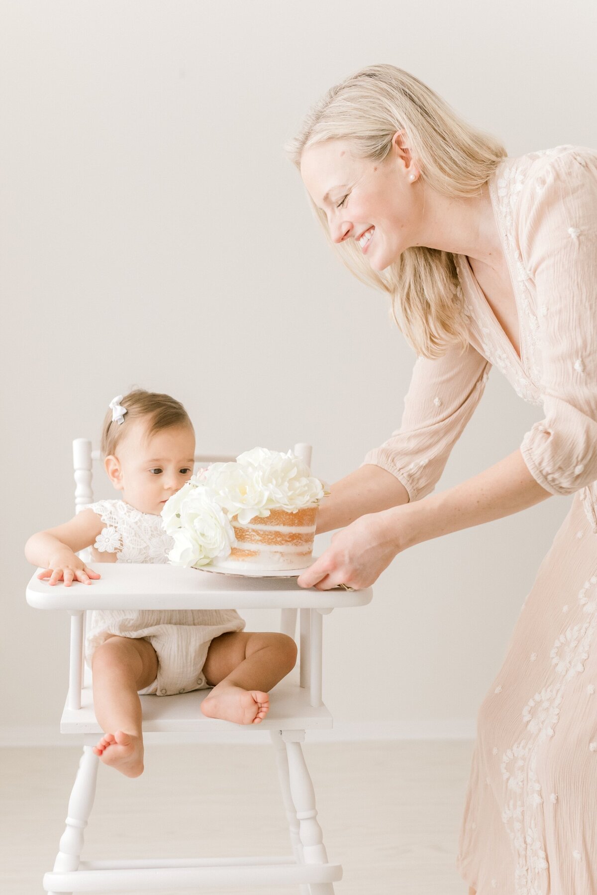 Houston first birthday photographer - adorable cake smash session with a happy one-year-old celebrating their big day in a beautiful antique high-chair in a private, Houston photography studio.