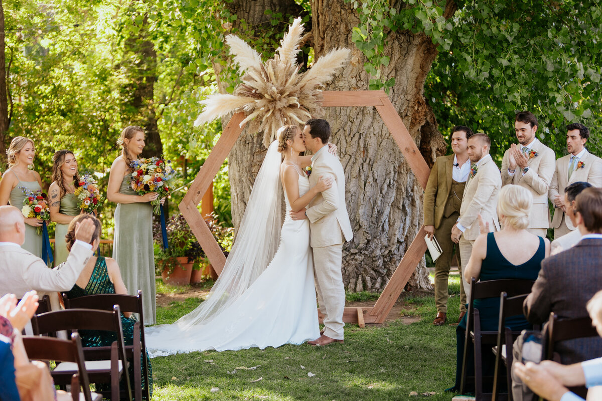 A bride and groom kiss during their wedding ceremony at Lyons Farmette in Lyons, Colorado.