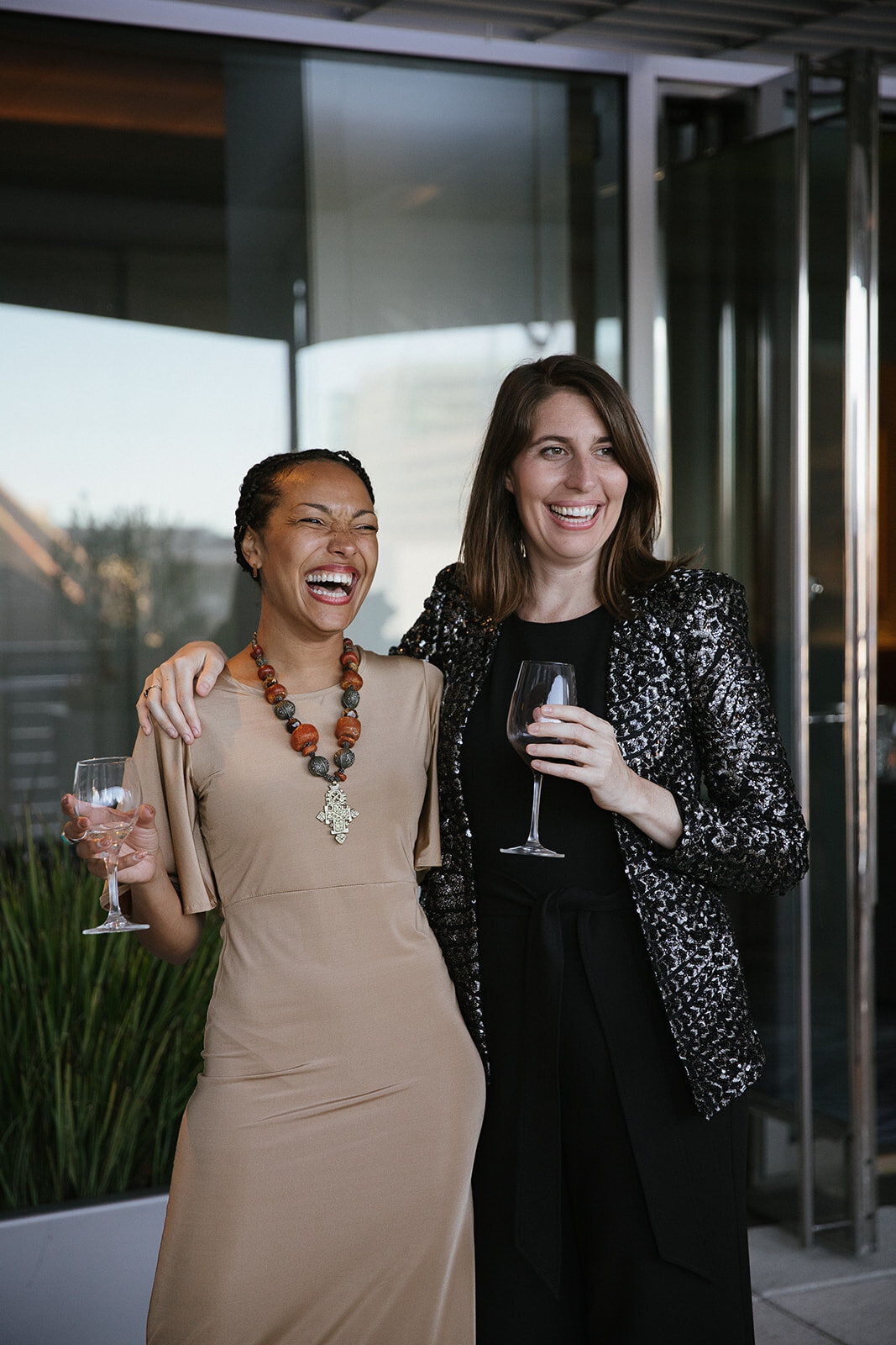 two women with a glass of wine laughing 