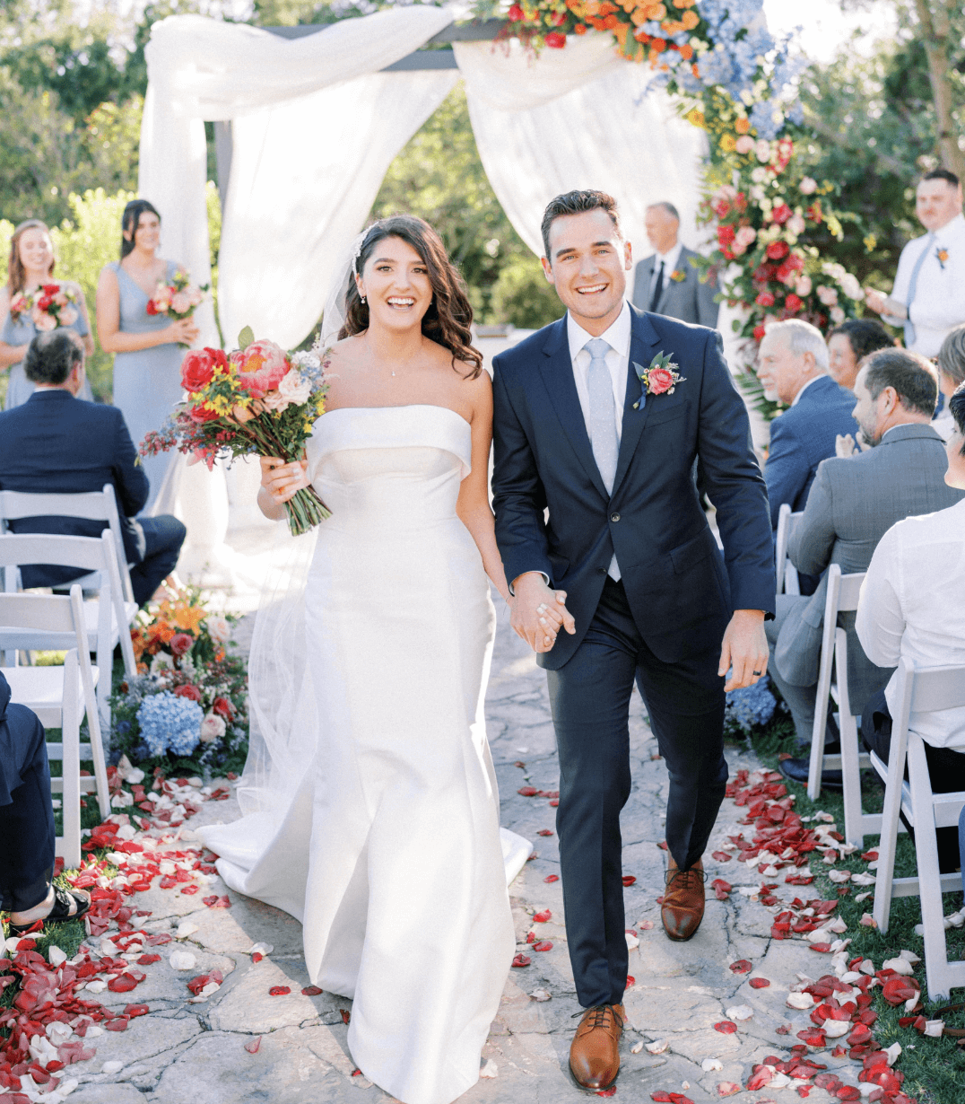Bride and groom walking down the aisle at an outdoor Austin wedding, showcasing hair and makeup services by Mistique Makeup for the big day