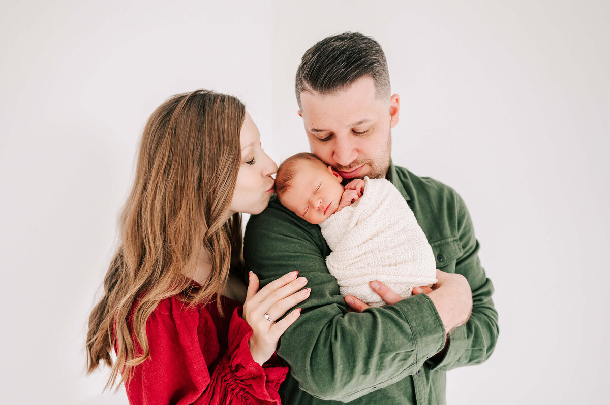 Springfield MO newborn photographer Jessica Kennedy of The Xo Photography captures dad holding baby with mom kissing his dad