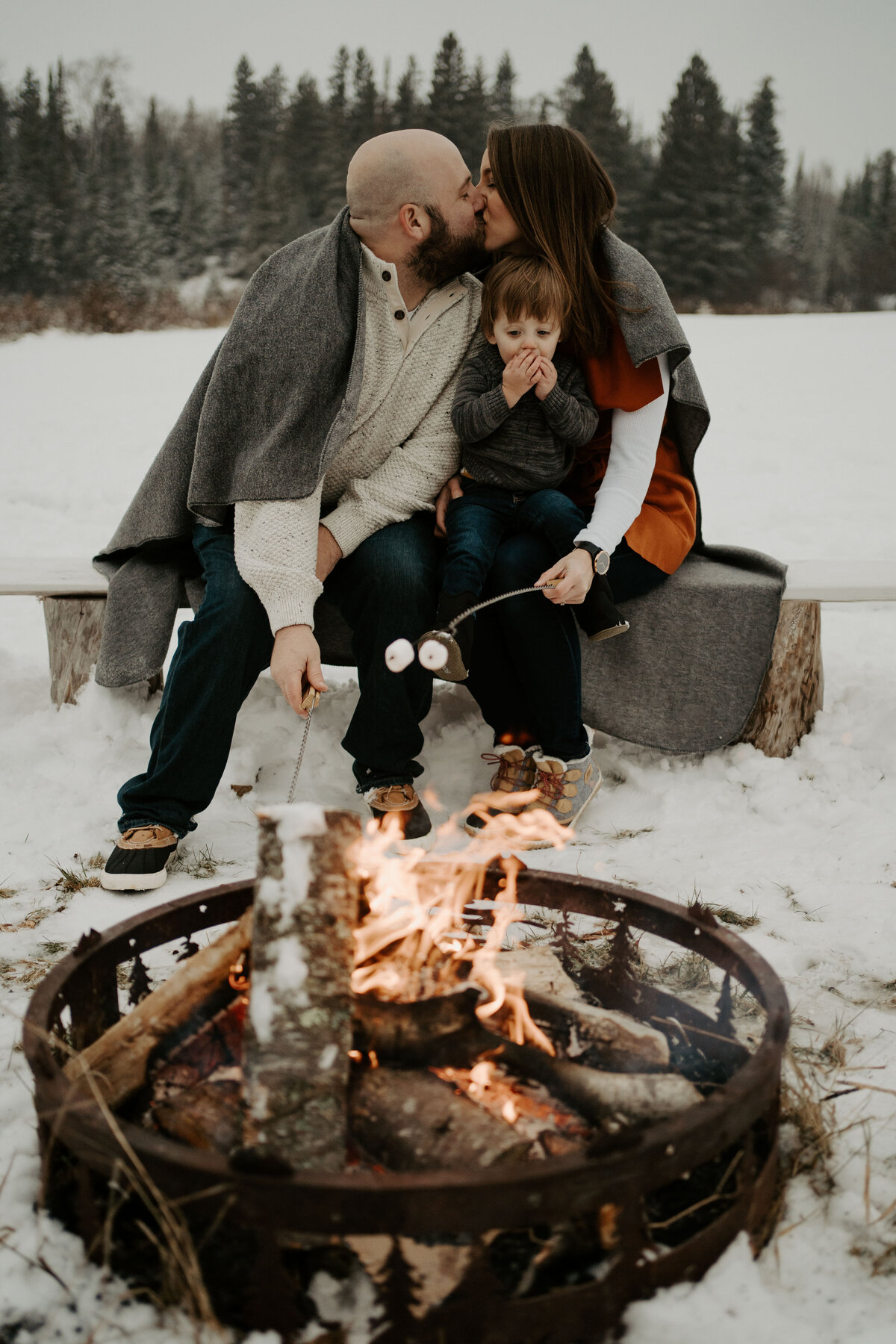 couple kissing holding child by bonfire