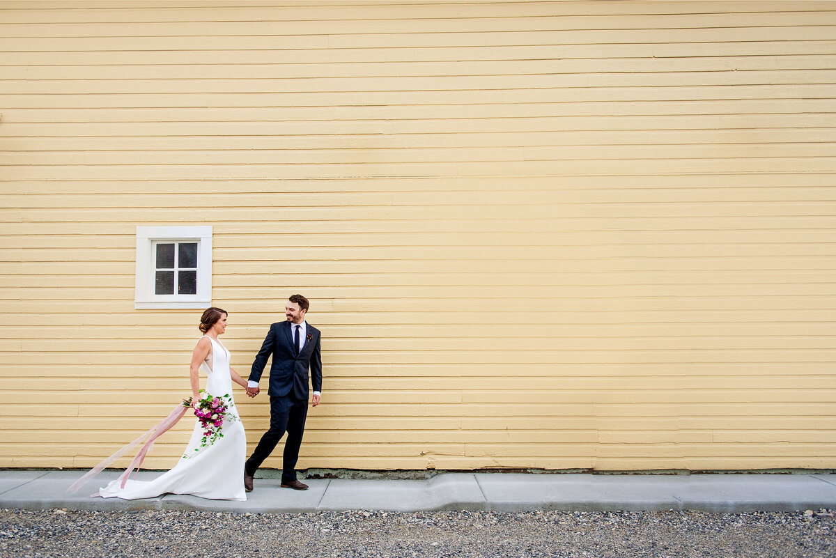 Couple walking together outside of a yellow barn