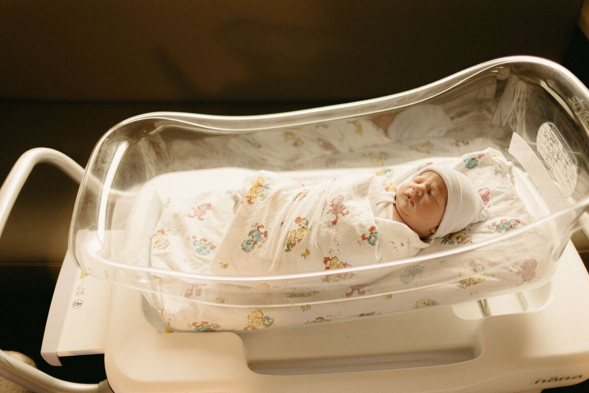 Brand new baby swaddled with hospital hat in Nashville Fresh 48 session.