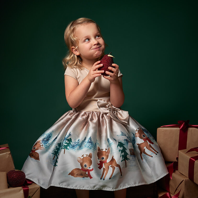 Image of a girl on a Christmas backdrop surrounded by presents in the studio. Taken by Norwich portrait photographer Claire Howes. Christmas Mini Sessions Norwich.