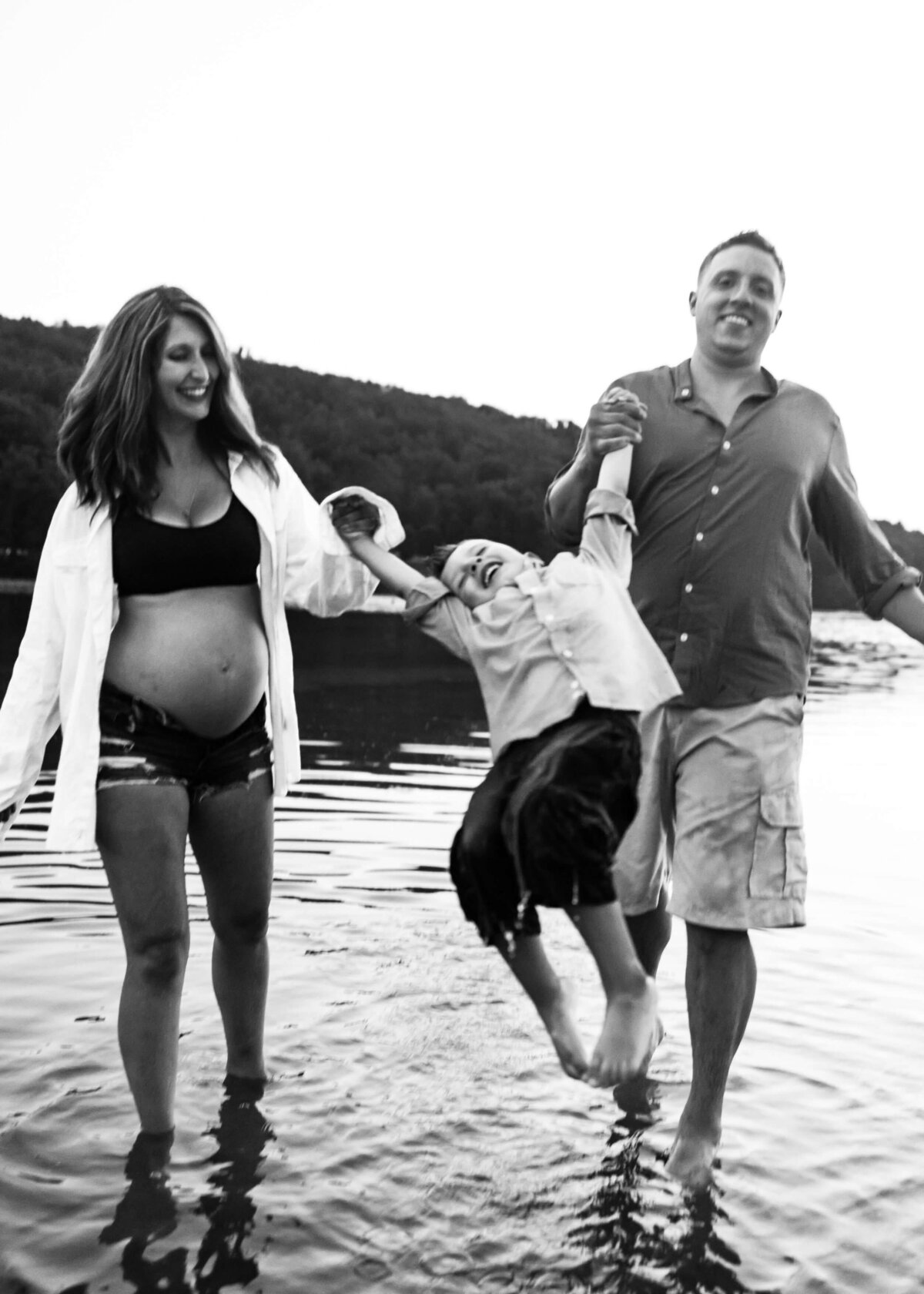 Black and white photo of a pregnant woman and her son in the water taken by a Pittsburgh maternity photographer.