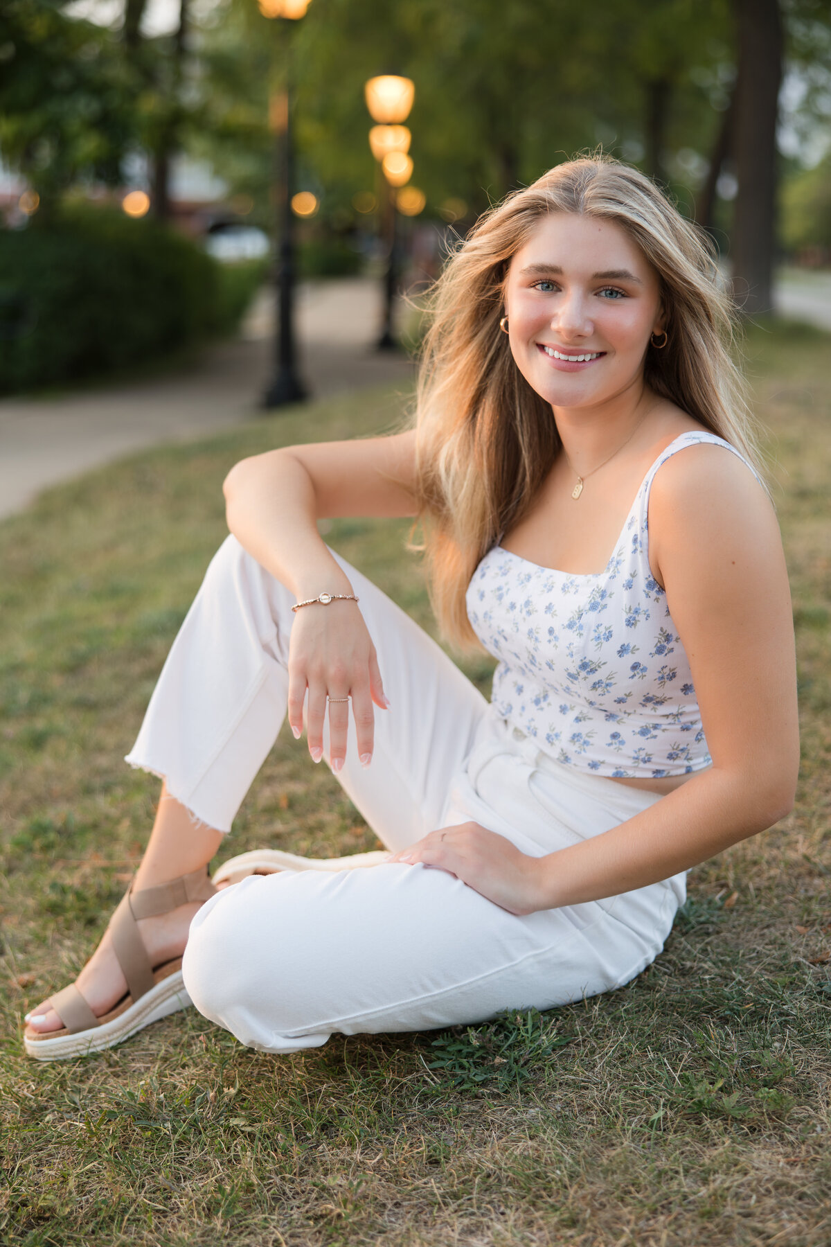 Senior girl seated in a park smiling at the camera
