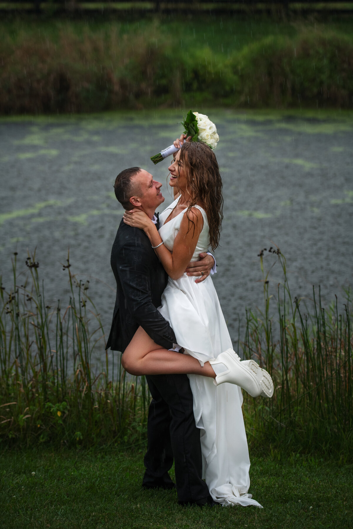Groom picked up her bride and getting soaked on their rainy wedding day