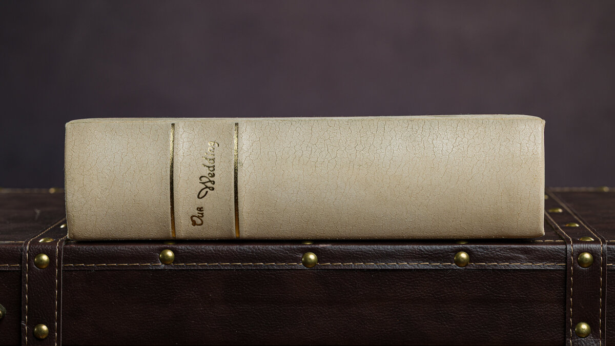 An old wedding album with 'Our Wedding' in gold lettering, lying on its side, symbolizing cherished memories.