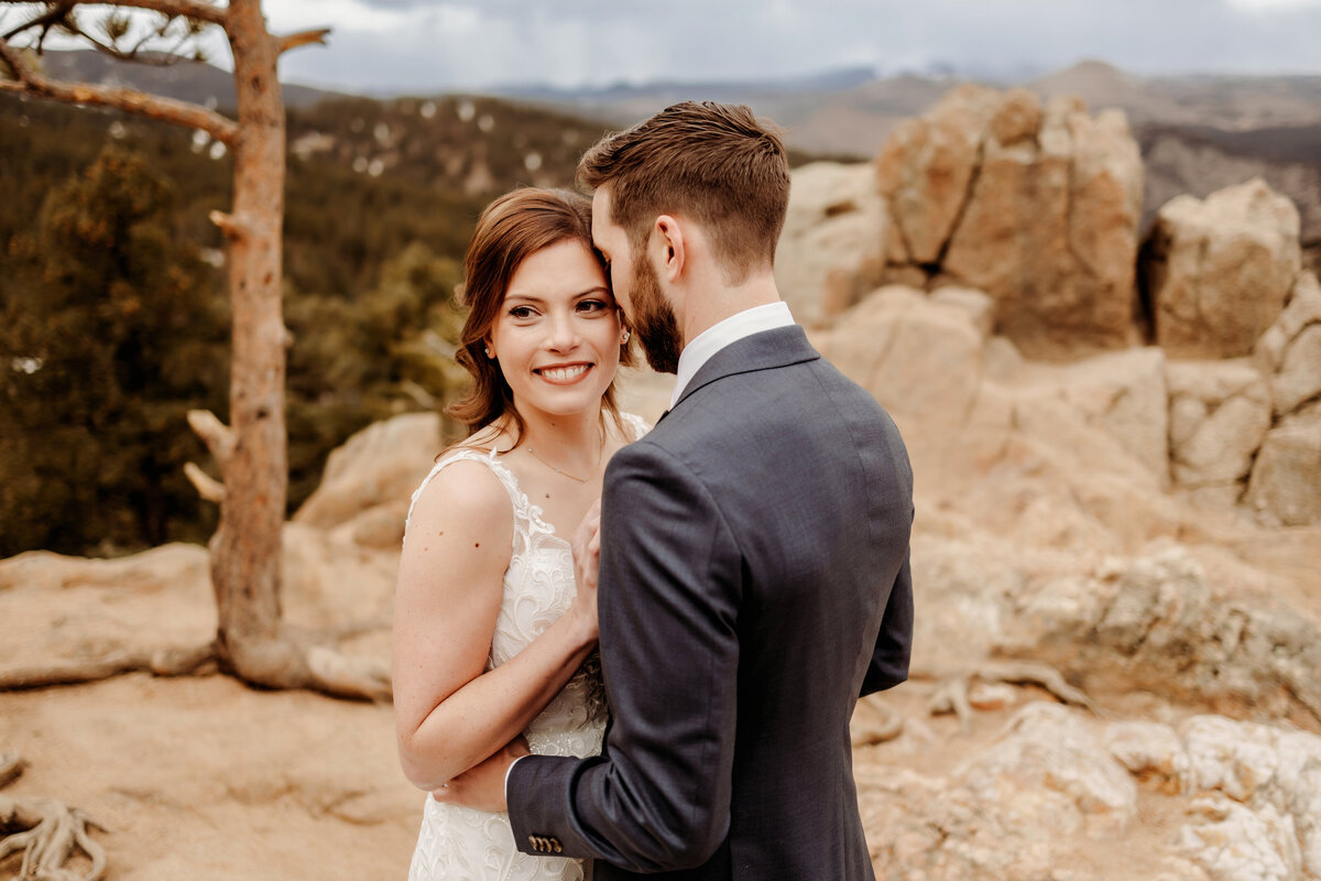 Husband kissing his new bride's temple on the top of a mountain during their First look in Boulder, COlorado