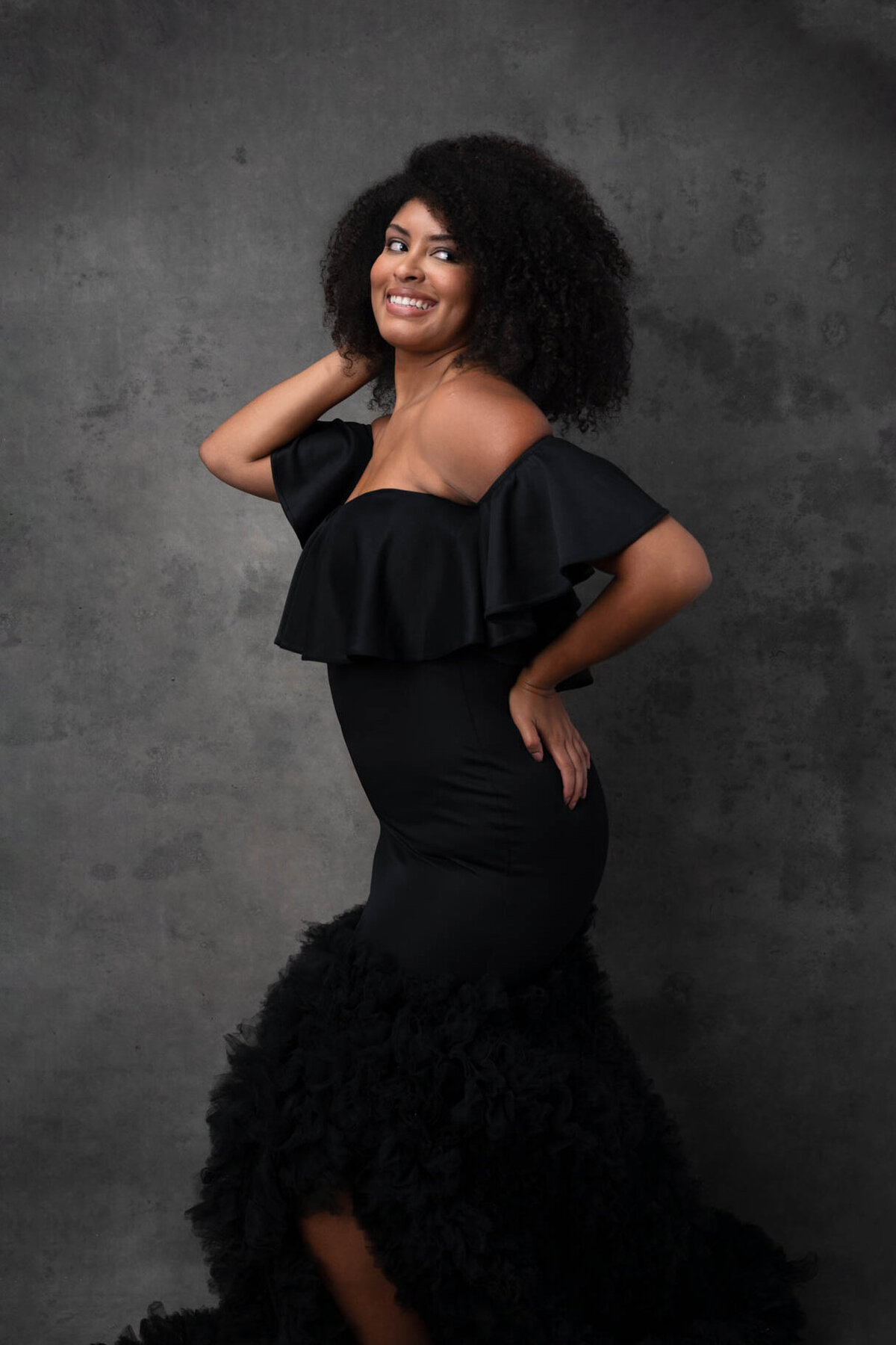 Woman posing smiling to camera wearing a black gown