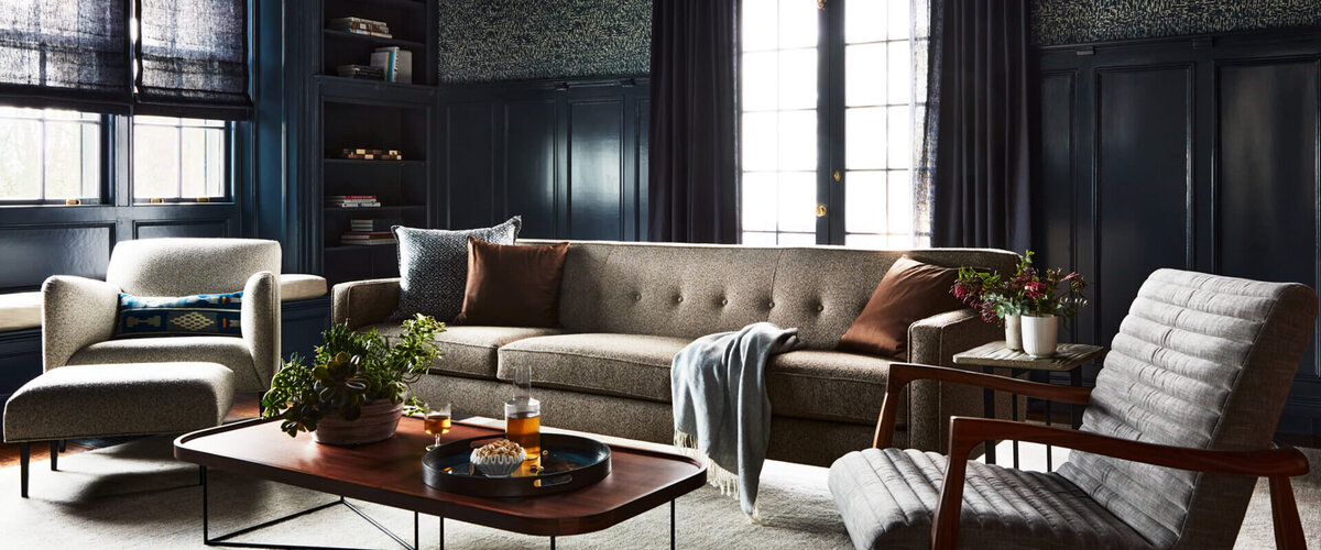 A historic home's media room with deep navy walls, original details, and mid-century modern furniture for a refined yet inviting space.