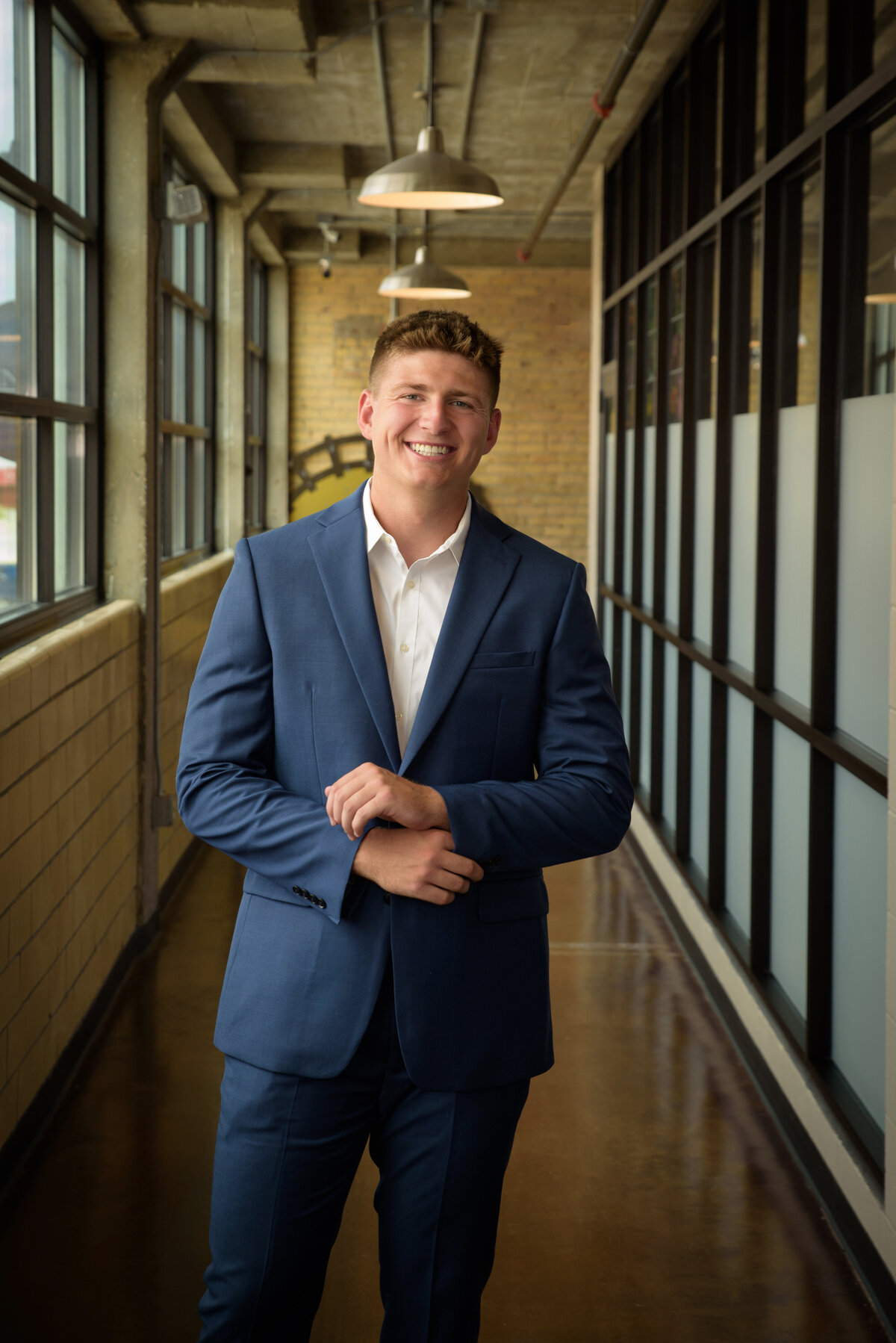 De Pere High School senior boy wearing a blue suit with white shirt standing in urban setting in Downtown Green Bay, Wisconsin