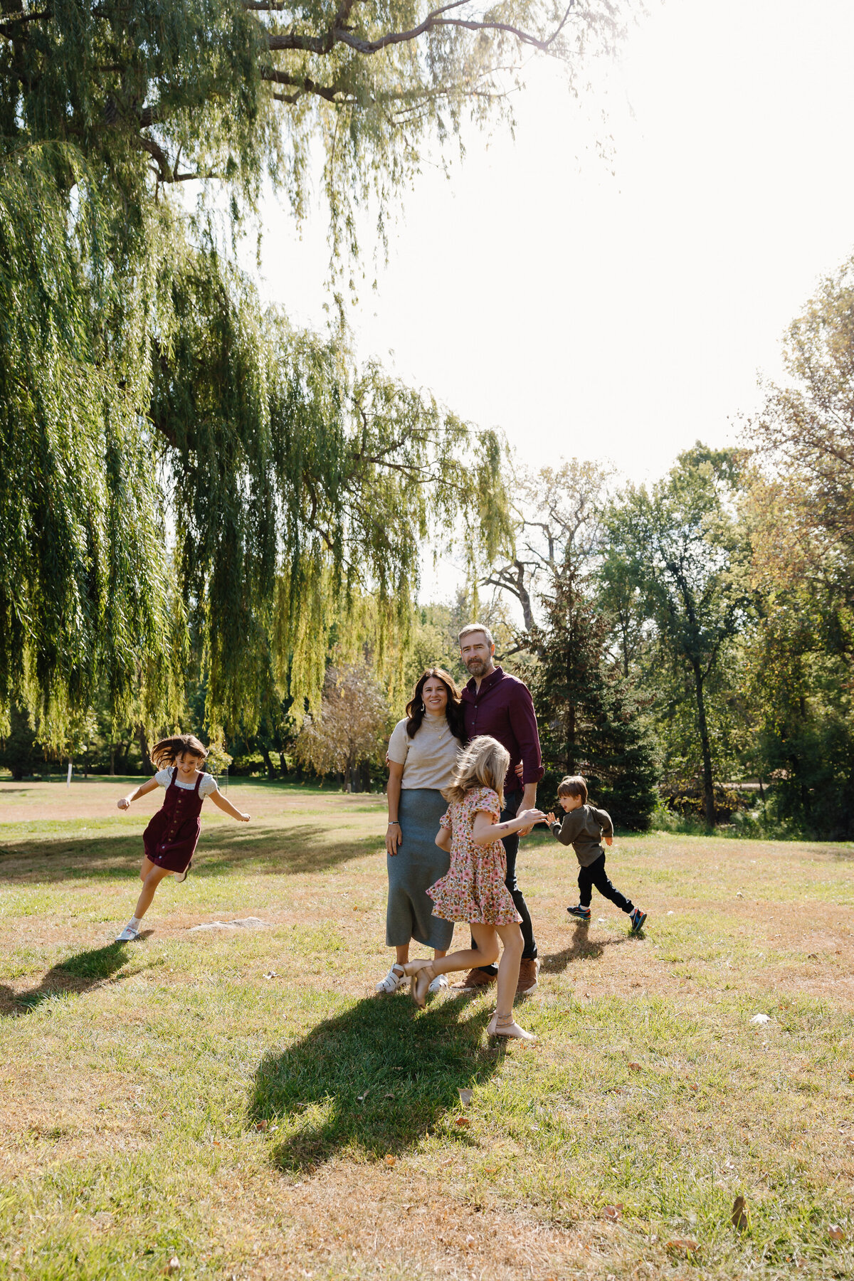 Kids running around their parents as they stand together