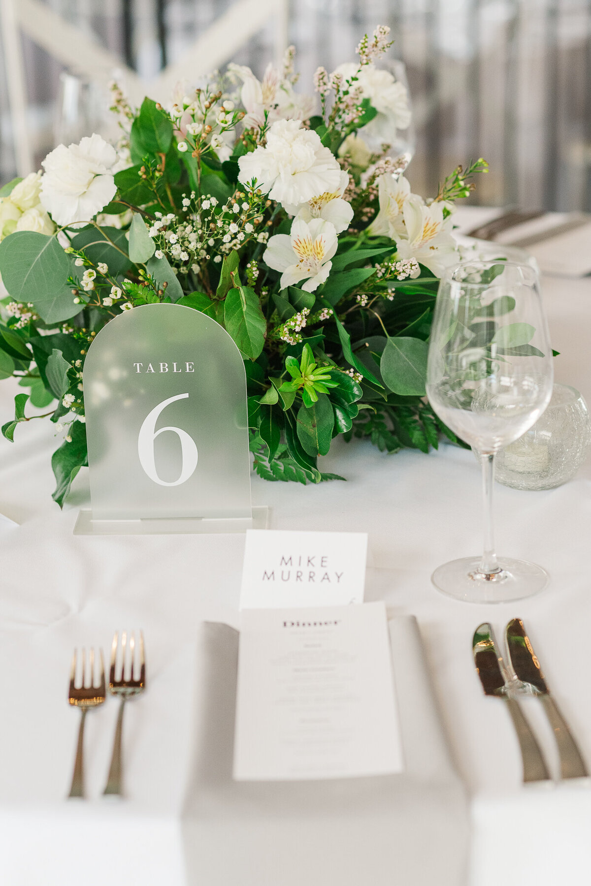 Close up of reception table captured by Denver wedding photographer with greenery, table setting, and menu