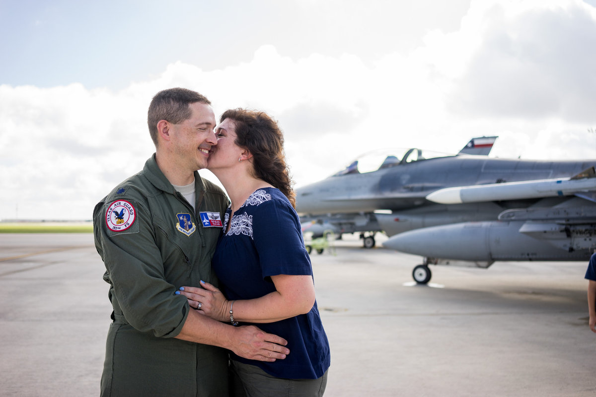 Air Force pilot and holding and kissing his wife in front of jet aircraft on San Antonio Air Force base.