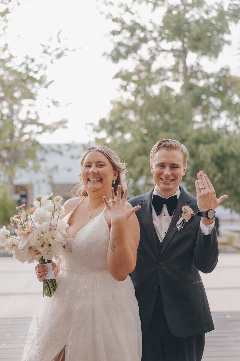 Couple smiling and holding up rings planned by travel planner for destination weddings CC Vacations