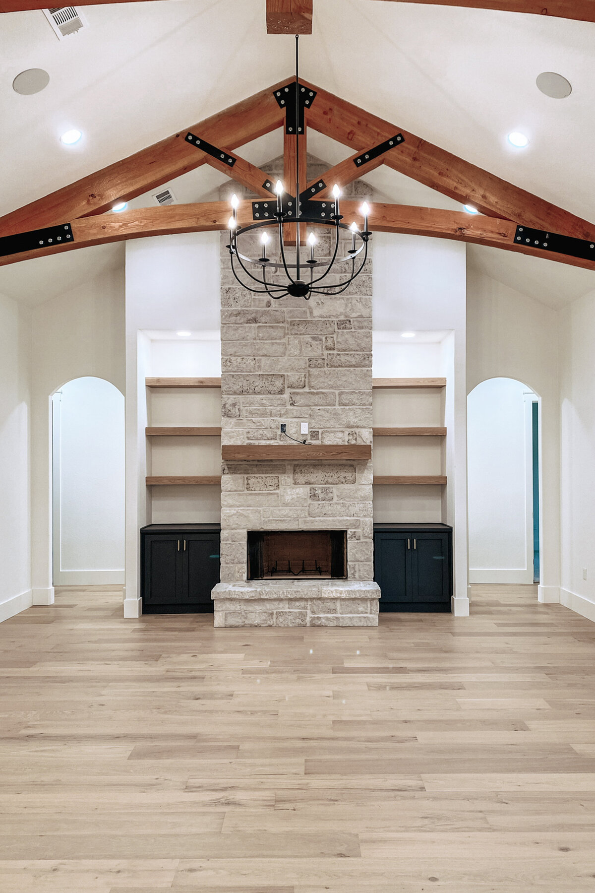 wood truss in living room with stone fireplace and built in cabinets on either side