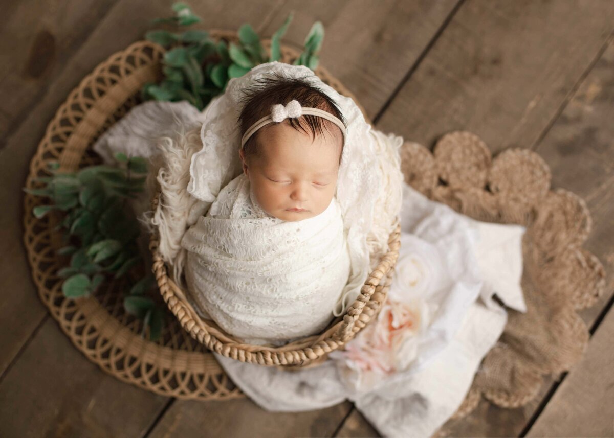 Newborn baby girl wrapped  in white on a boho setup
