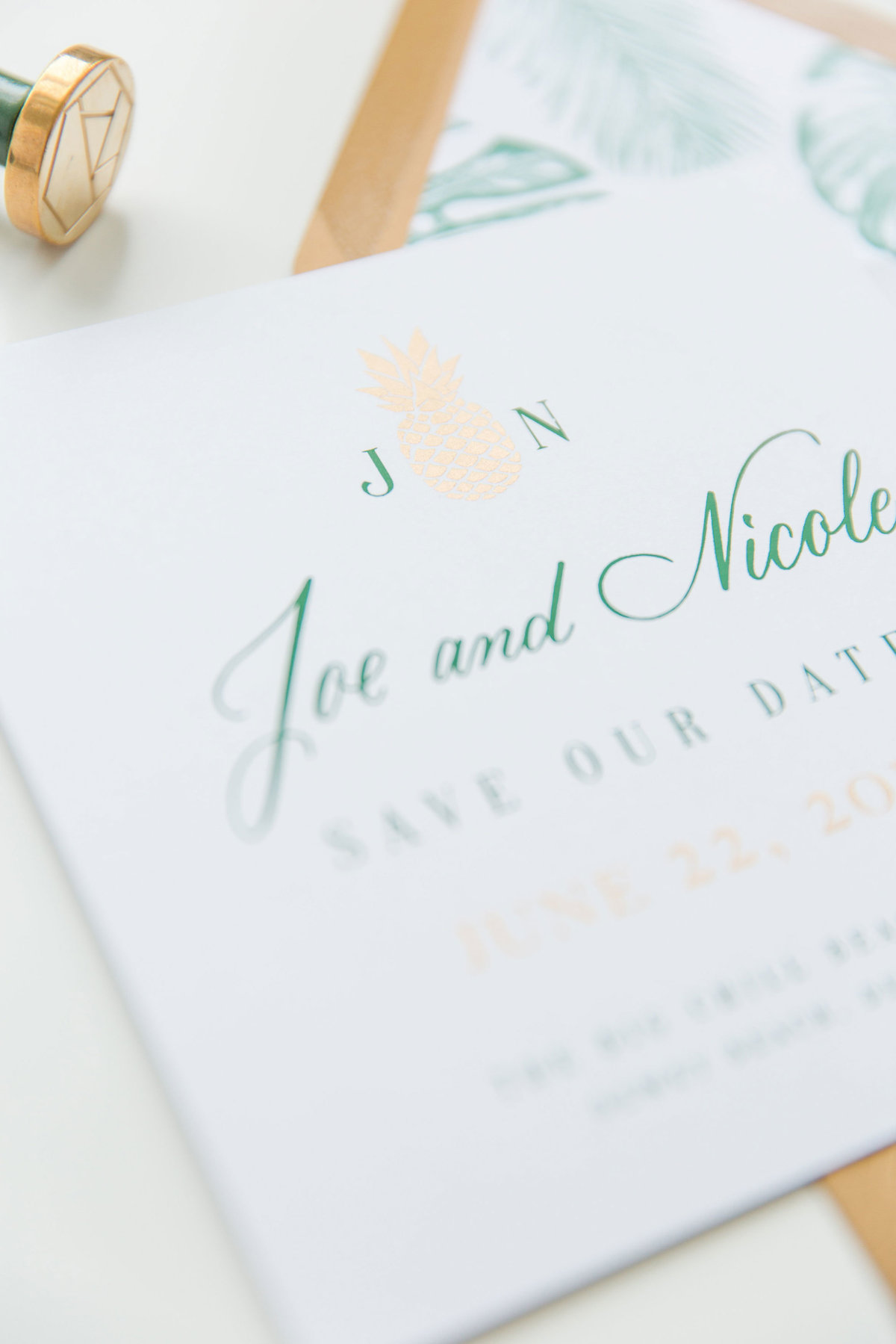 Closeup of gold ink pineapple with green calligraphy on wedding save the date by Lewes Lettering Co