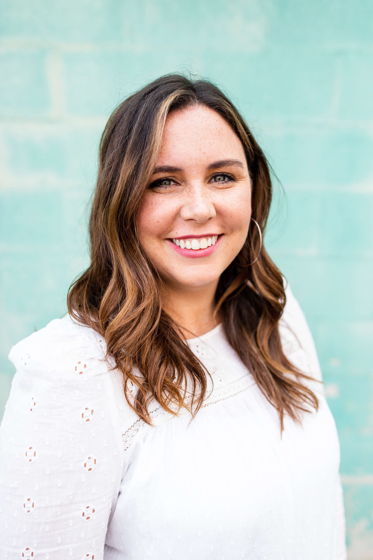 Headshot of brunette in front of blue brick wall