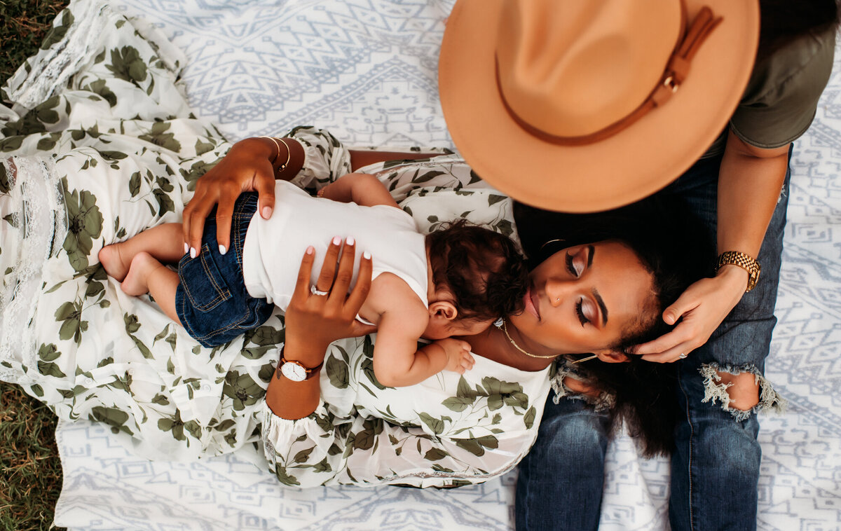 Mom is laying with baby on her chest on her wife's lap.