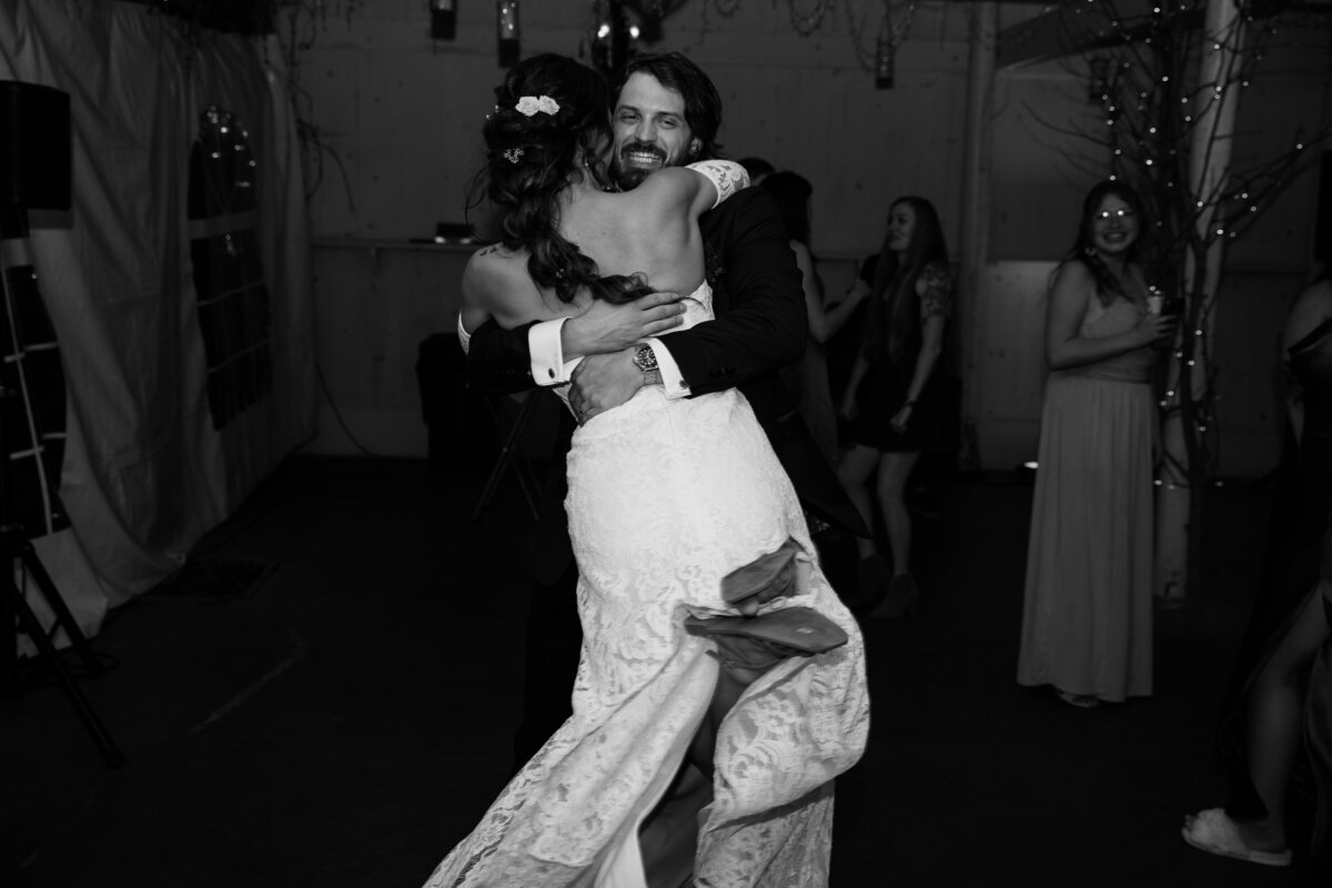 bride jumping up and hugging her groom in excitement to being married