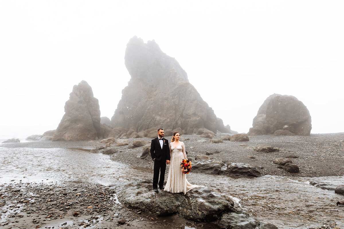 Bride & groom standing in front of Ruby Beach sea stacks on their foggy elopement day in Olympic National Park!