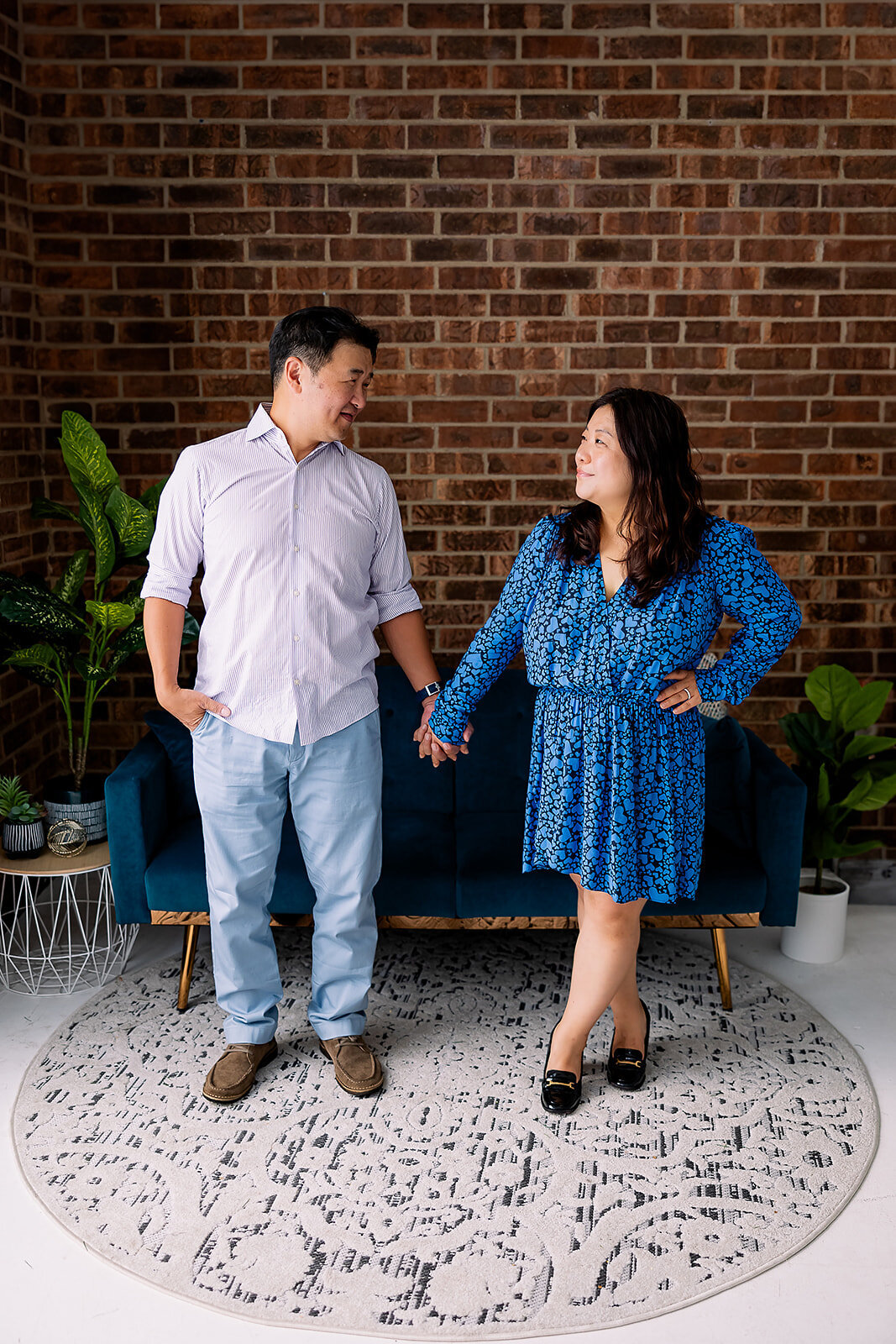 Man and woman hold hands and stare at each other in front of a couch