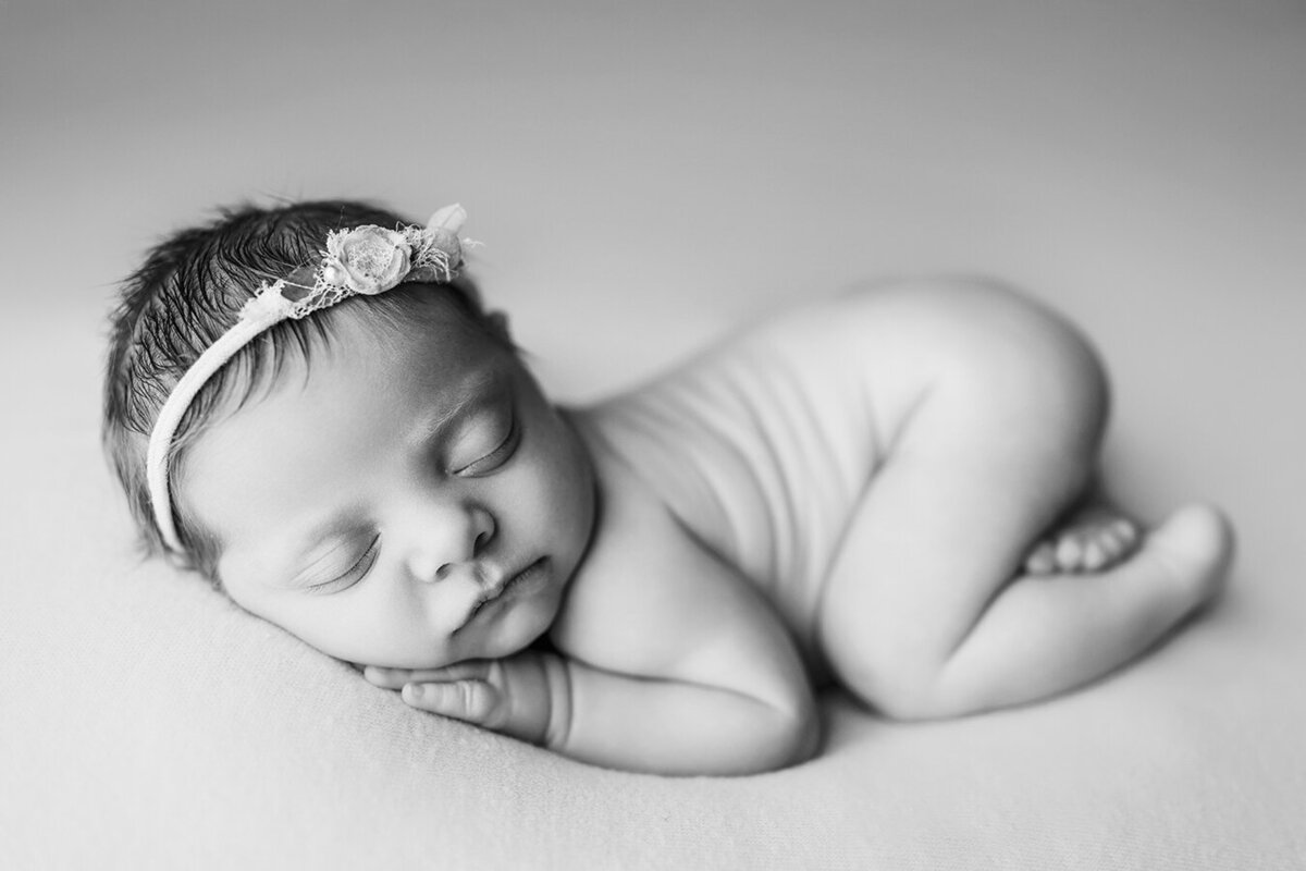 newborn baby girl sleeping on her belly in a black and white photo