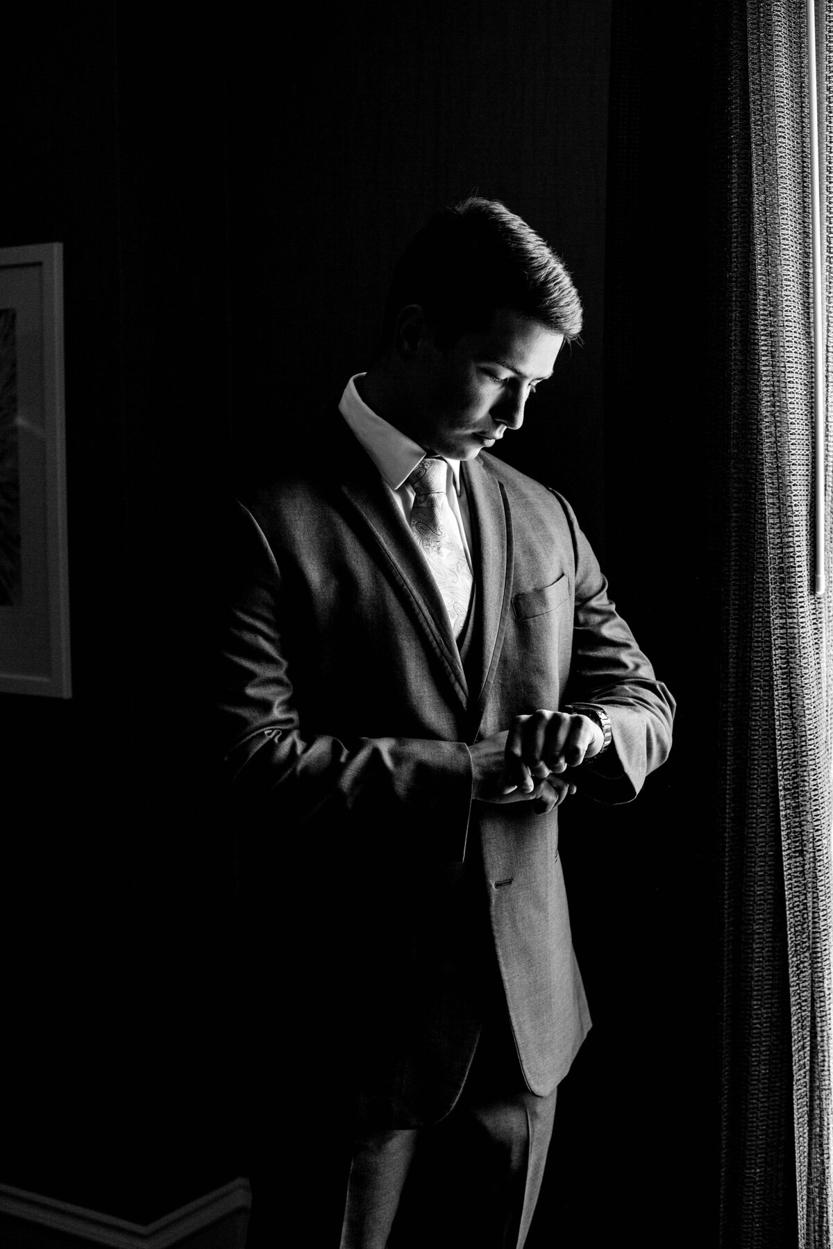 Black and white photo of groom checking the time on his watch