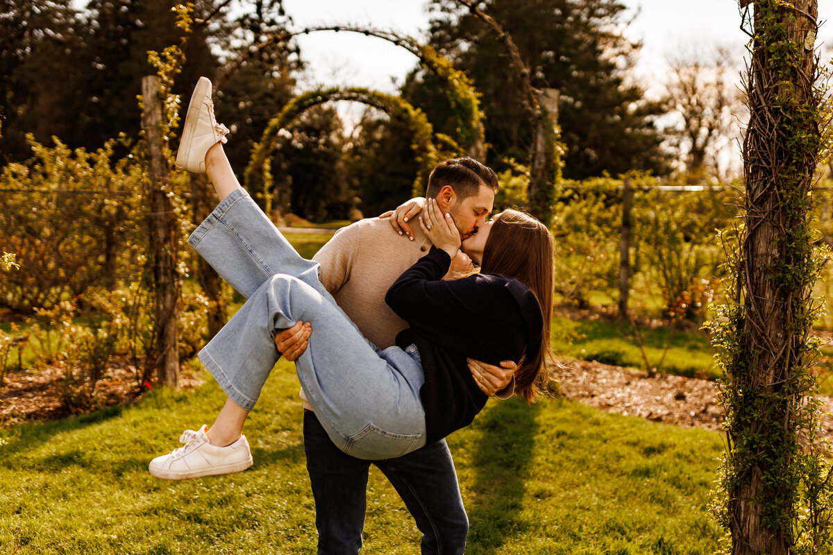 an engaged couple kisses as a woman is being lifted by the man