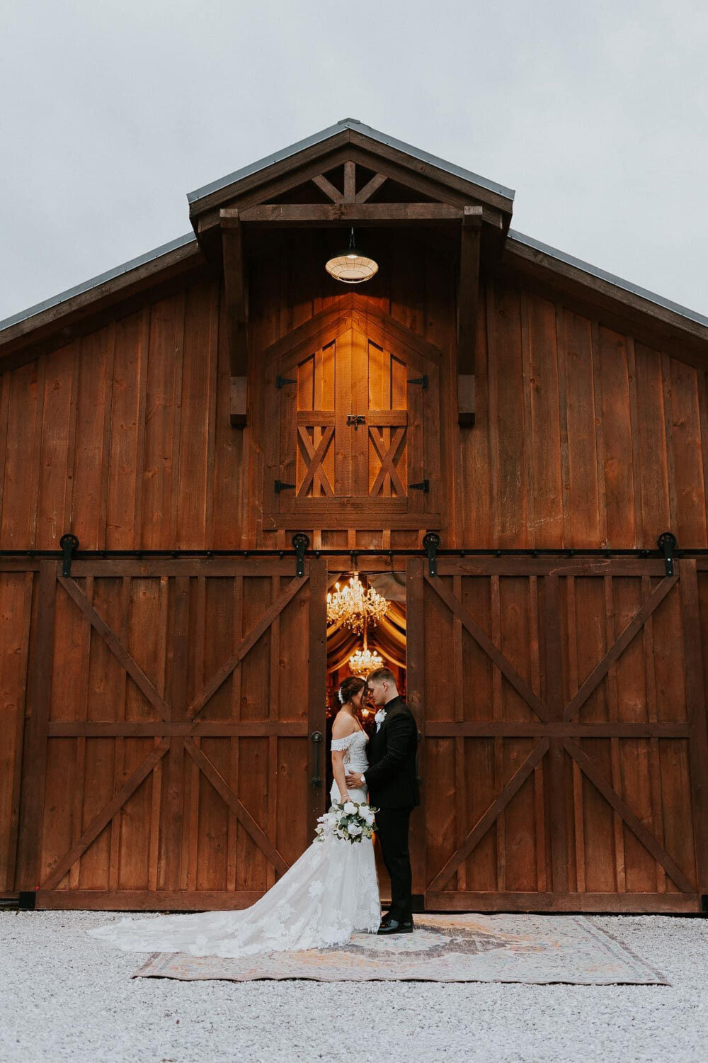 Bride and groom sharing a moment in front of a barn with large wooden doors