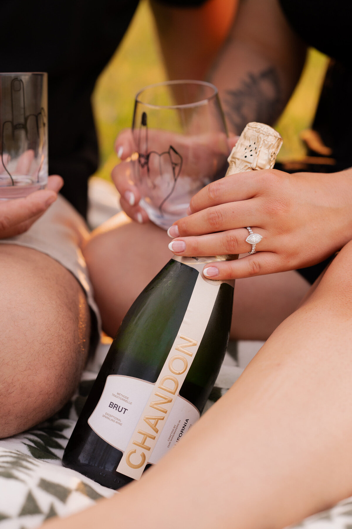 Popping bottles of champagne to celebrate their upcoming wedding during their engagement session at Hudson Crossing Park in Schuylerville, NY.