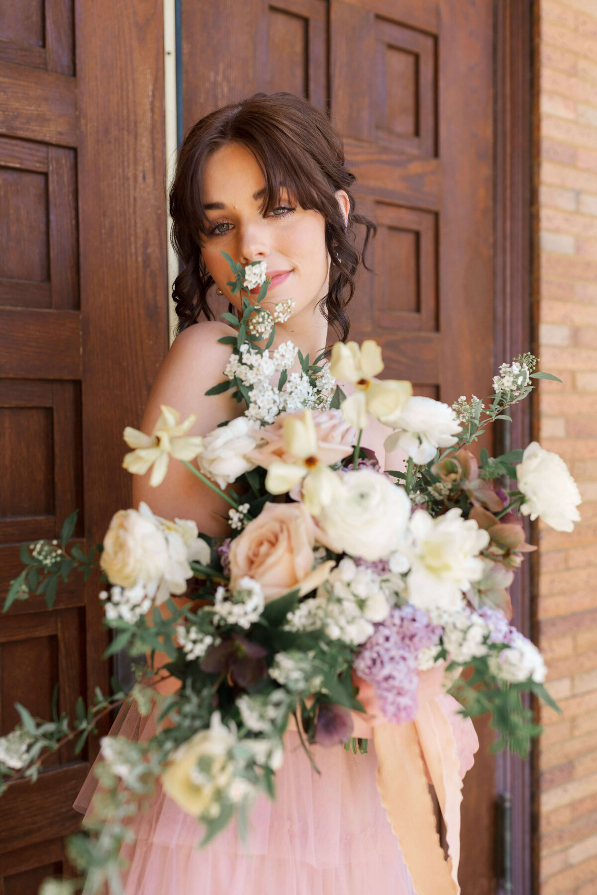 woman holding large bouquet of flowers in ivory, peach, pale pink, lavender and greenery