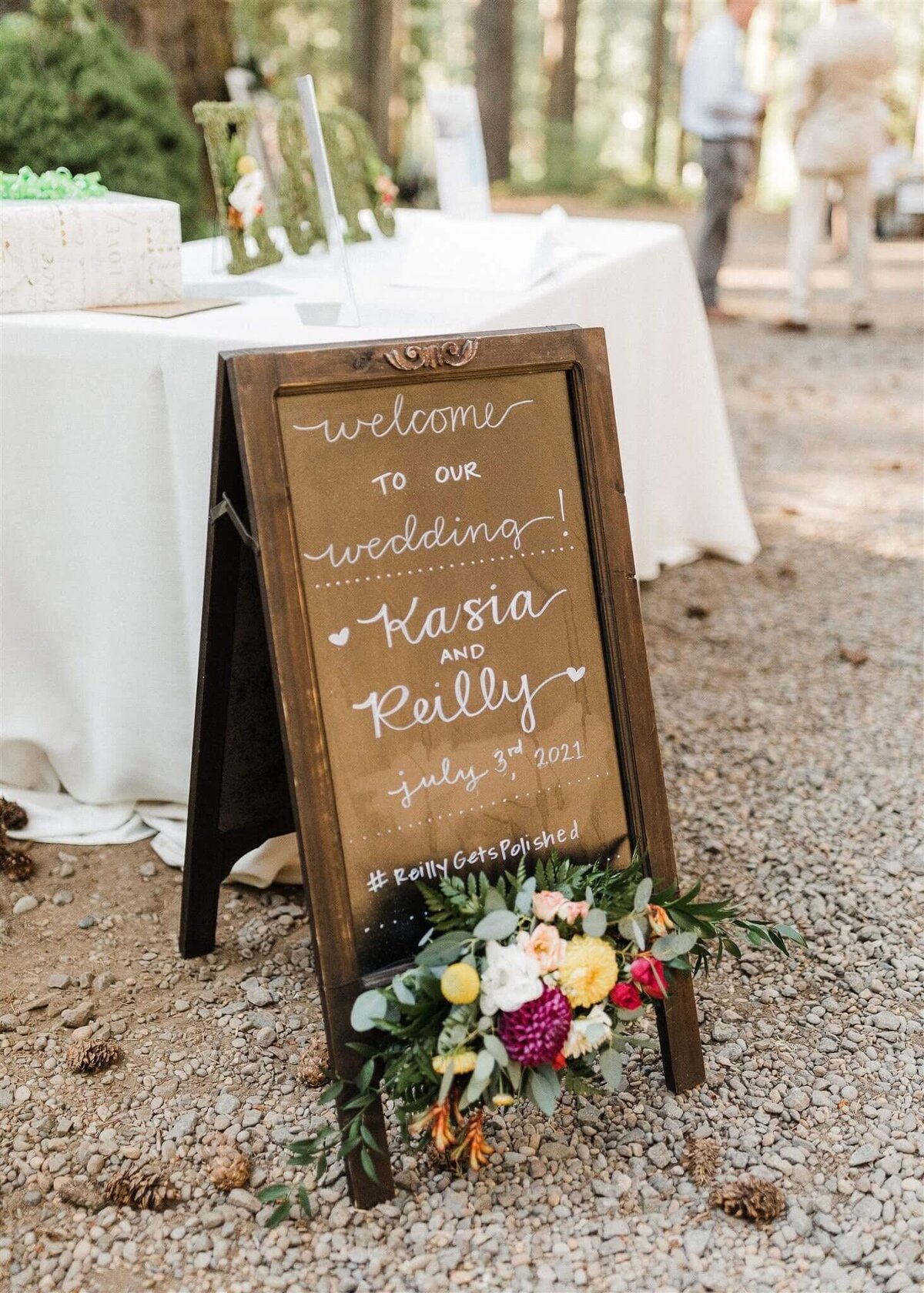 Floral arrangement sits atop a wedding welcome sign.