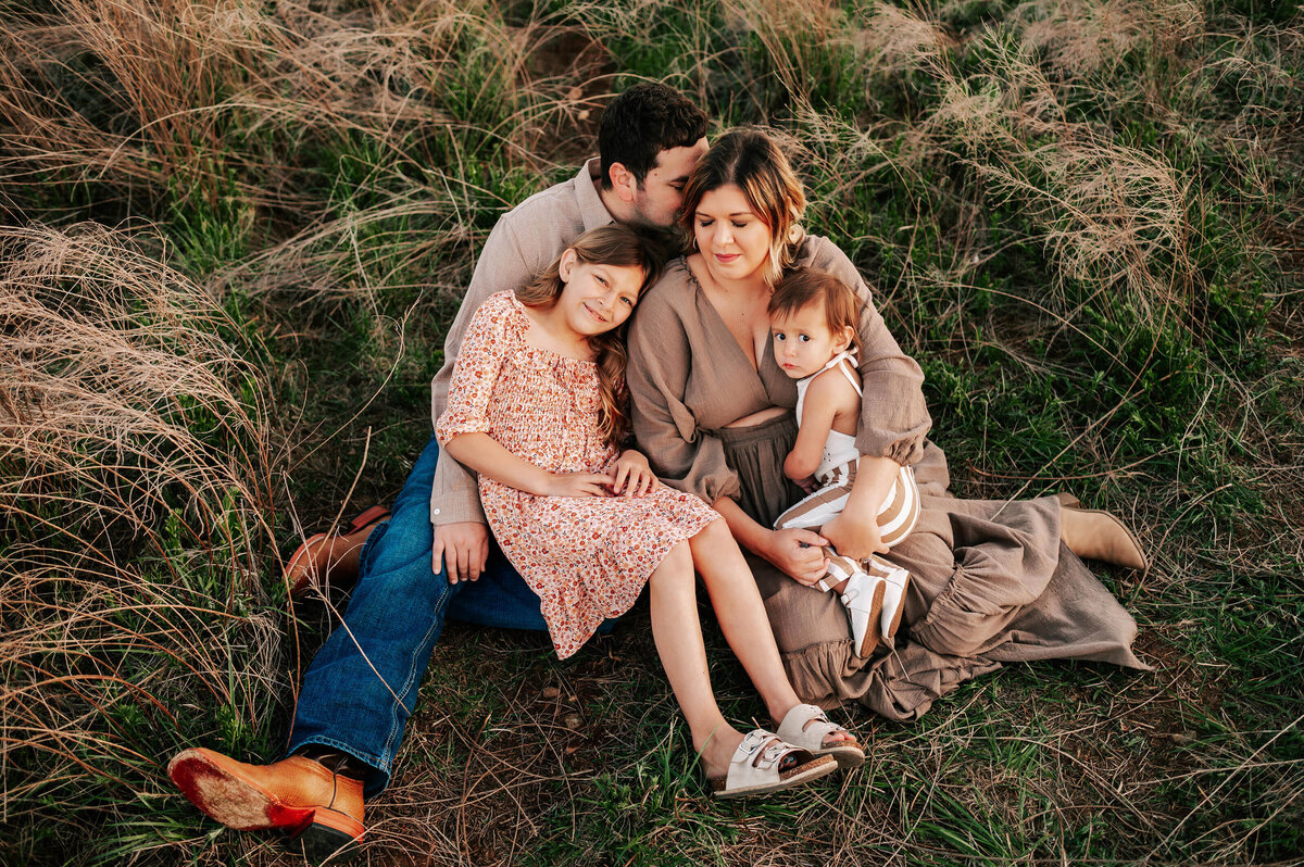 family sitting on each other lap in field during Springfield MO family photography session